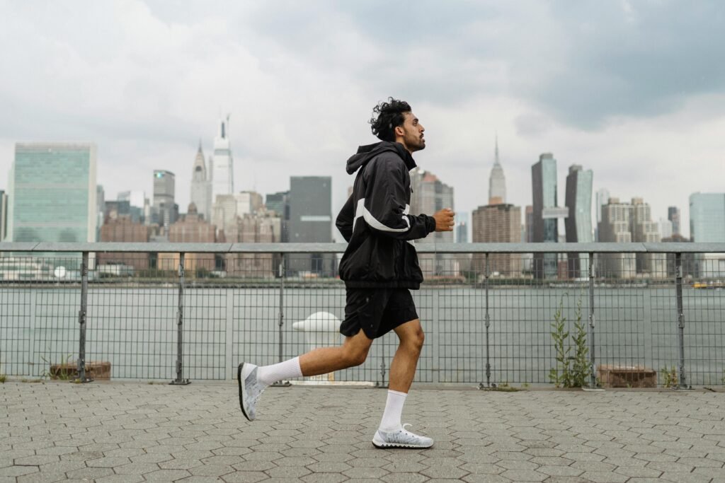 pexels photo 5039659 5039659 Adult man jogging along a waterfront with the New York City skyline in the background, exuding a vibrant urban lifestyle.