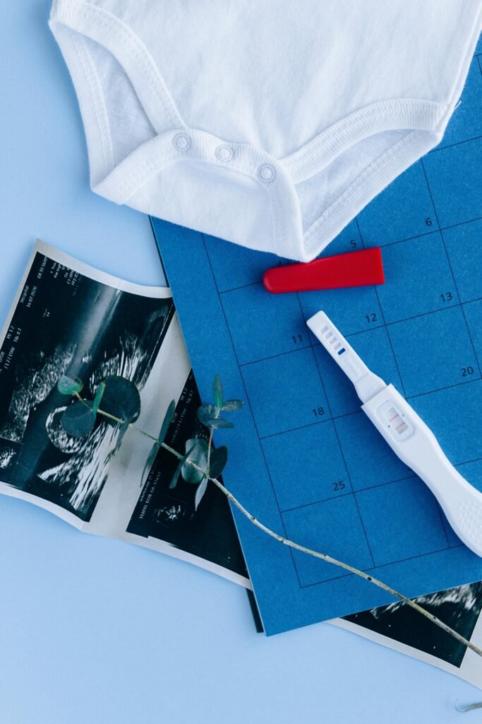 pexels photo 5982374 5982374 Flat lay of a positive pregnancy test with baby clothes and ultrasound images, symbolizing new life.
