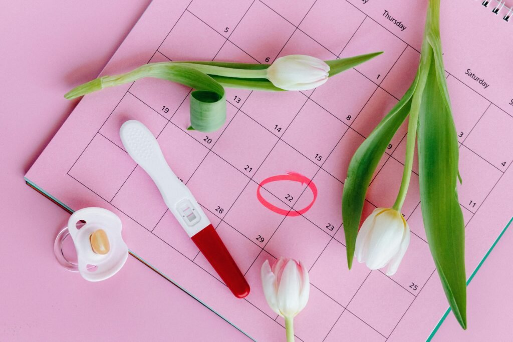 pexels photo 5982466 5982466 Pregnancy test on pink calendar with tulips, symbolizing fertility and new beginnings.