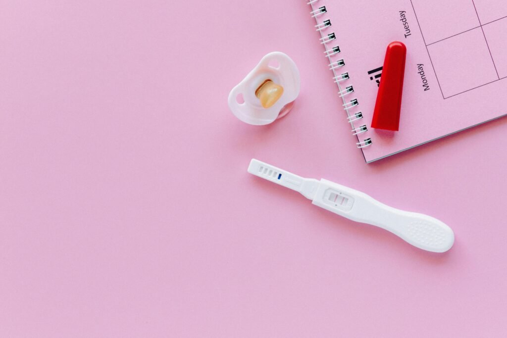 pexels photo 5982472 5982472 A positive pregnancy test on a pink surface with a pacifier and planner.