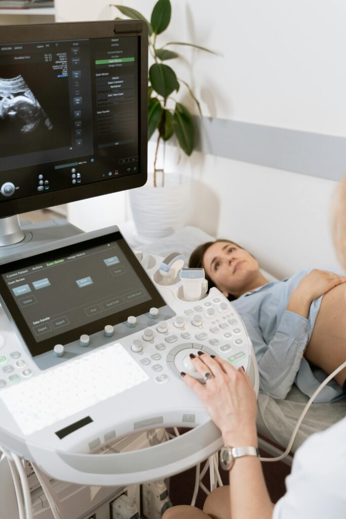 pexels photo 7088841 7088841 Pregnant woman undergoes ultrasound scan by medical professional in hospital room.
