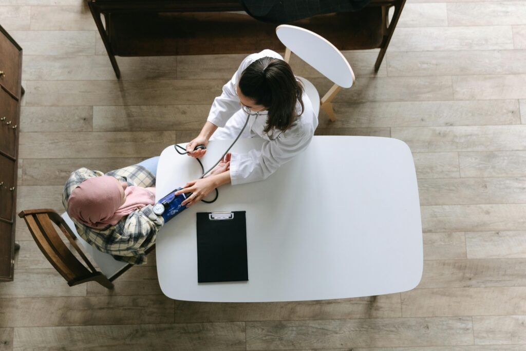 pexels photo 7659565 7659565 Overhead view of a doctor checking a patient's blood pressure during a healthcare consultation indoors.